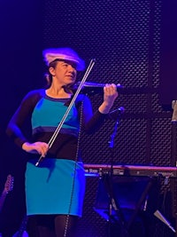 a woman in a blue dress playing a violin on stage