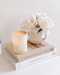 a candle sits on a table next to books and flowers