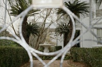 a white gate with a fountain and palm trees