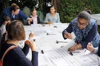 a group of people working at a table with paper and pencils