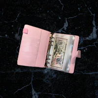 a pink leather wallet with money in it