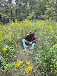 a man sitting in the middle of a field of yellow flowers