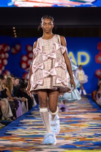 a model walks down the runway in a plaid dress