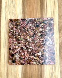 a pink stone coaster on top of a wooden table