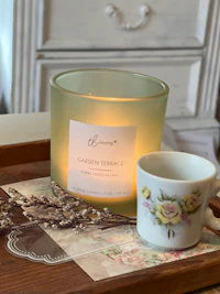 a candle sits on a tray next to a cup