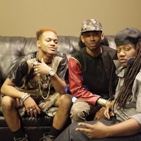 three men with dreadlocks sitting on a couch