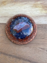 a blue and red stone brooch on a wooden table