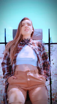 a woman in a plaid shirt and tan pants sitting on a chair