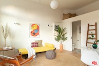 a living room with a yellow couch and a ladder