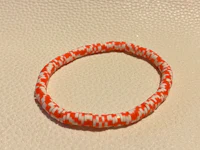 an orange and white braided bracelet on a white surface