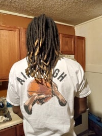 a man with dreadlocks standing in a kitchen