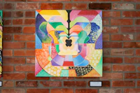 three paintings hanging on a brick wall