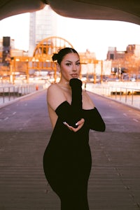 a woman in a black dress posing on a bridge