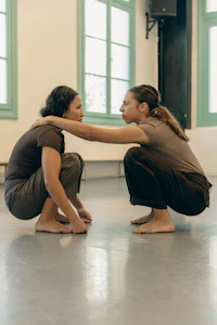 two women crouching on the floor in a dance studio