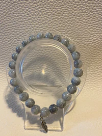 a bracelet with gray beads on a white surface
