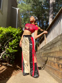 a woman in a red top and black pants posing on a sidewalk