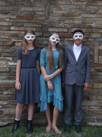 a group of children wearing masks in front of a brick wall