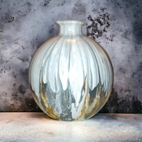 a white and gold vase sitting on top of a concrete wall