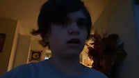 a boy in a gray shirt is staring at the camera