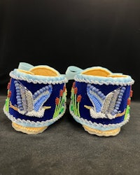 a pair of blue beaded shoes with birds on them