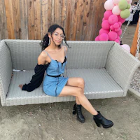 a woman is sitting on a bench with balloons in the background