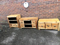 three wooden tv stands in front of a brick wall