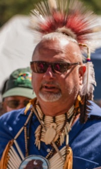 a man wearing a feathered headdress and sunglasses