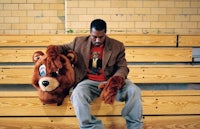 a man sitting on a bench holding a stuffed bear