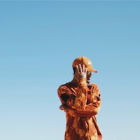 a man in an orange camouflage jacket standing in the desert