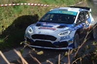 a ford fiesta rally car driving down a dirt road