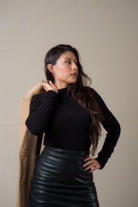 a woman wearing a black turtleneck and leather skirt