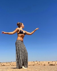 a woman standing in the desert with her arms outstretched