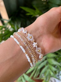 a woman's wrist with a gold and white bracelet