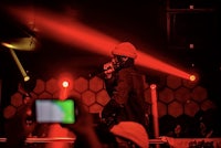 a man with a microphone on stage in front of red lights