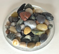 a bowl full of rocks and pebbles on a white surface