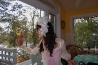 a woman in a white dress standing in front of a window