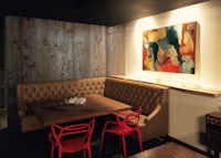 a dining room with a wooden wall and red chairs