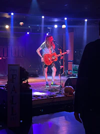 a woman playing an acoustic guitar on stage