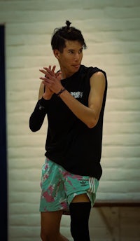 a young man in a black shirt and shorts is playing a game of frisbee