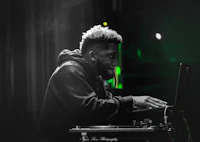 a black and white photo of a man djing on a laptop