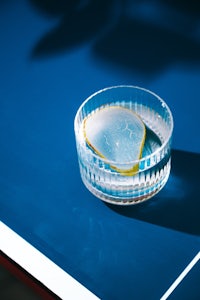 a glass bowl with a slice of lemon sitting on top of a blue ping pong table