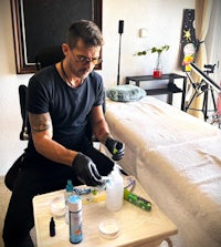 a man sitting in a chair with a bottle of tattoo ink