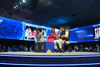 a group of people sitting on a stage in front of a large screen