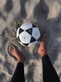 a person standing next to a soccer ball in the sand