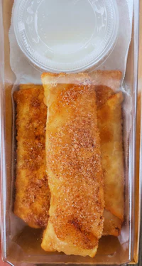 a box containing a cinnamon roll and a cup of milk