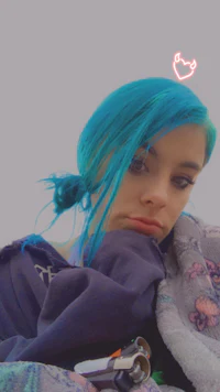 a girl with blue hair laying on a blanket