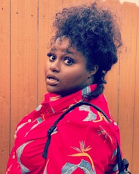 a woman wearing a red shirt and carrying a backpack