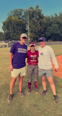 three people posing for a picture on a baseball field