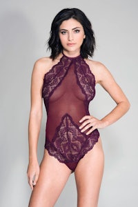a woman is posing in a burgundy lace bodysuit