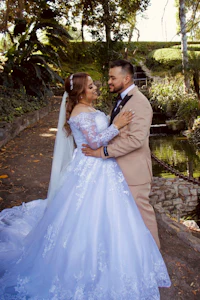 a bride and groom embracing in front of a pond